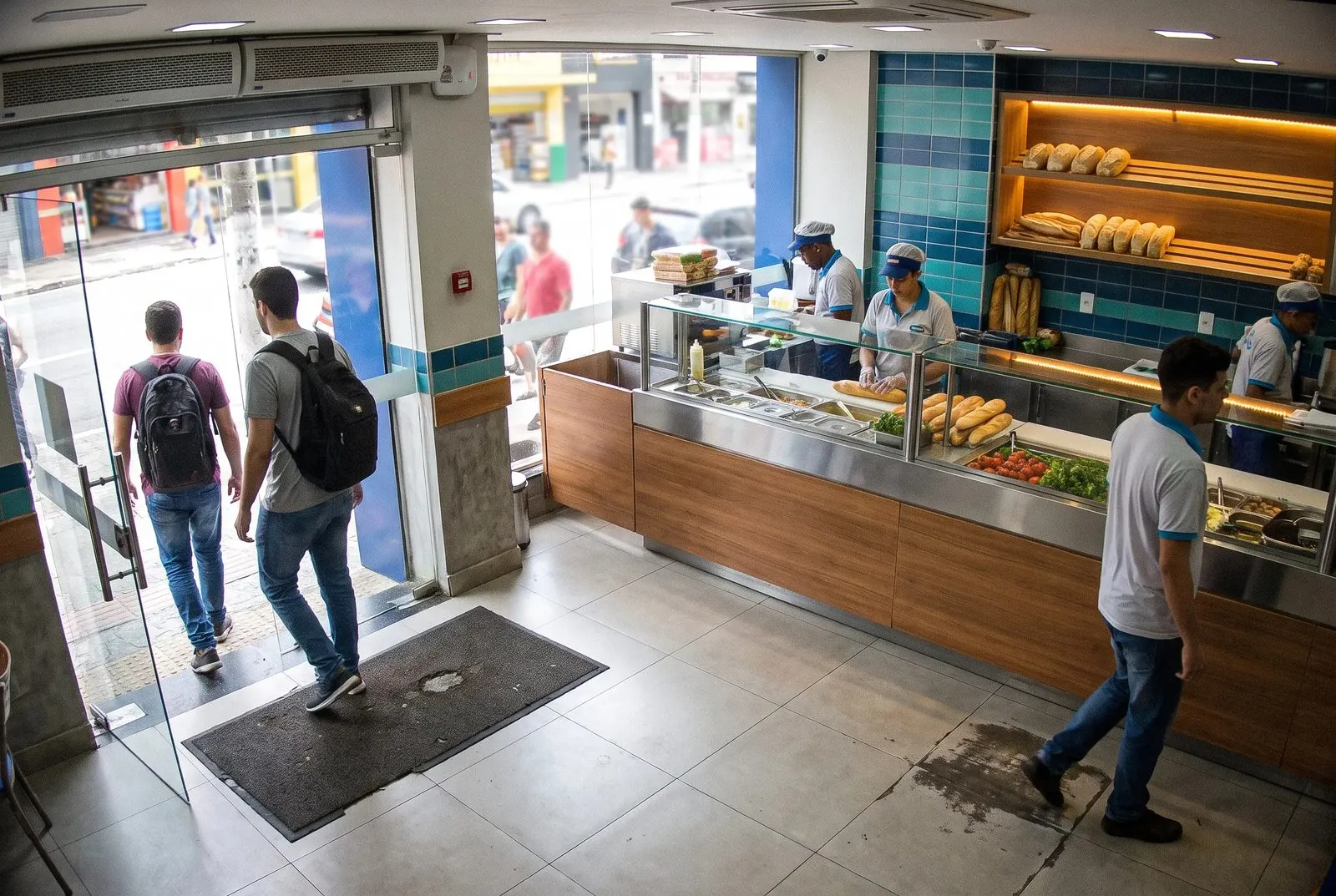 Entrada da loja vista de dentro, com clientes passando pela porta